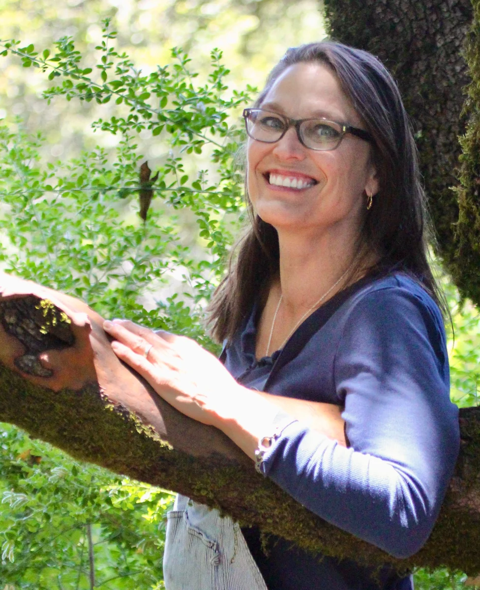 Patty Purpur de Vries smiling in the sunlit redwoods