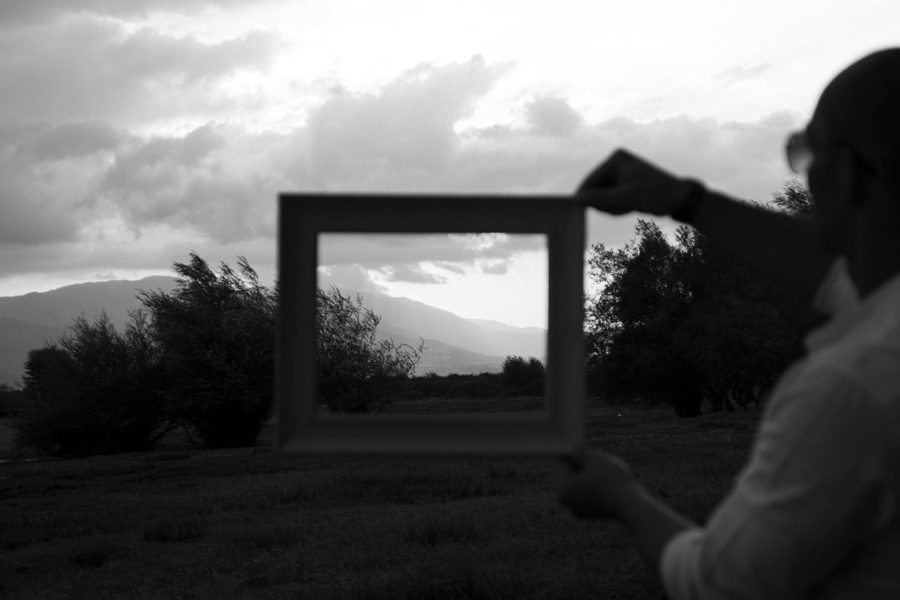 A person holding an empty frame up to a landscape, choosing what to see